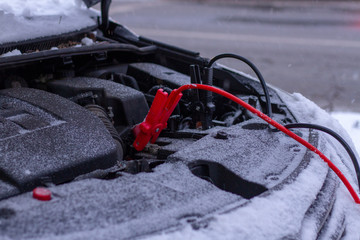 Quickly charge the car battery with jumper cables and another car. Open car hood with battery wires...