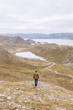 Young man standing on a hill, looking over Lake Inari, Finland