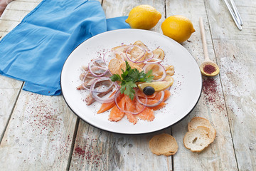 Assorted fish sliced ​​on a white plate on the table. restaurant menu with salmon fillet. thin slices of red fish with lemon. restaurant concept.