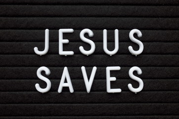The words Jesus Saves in white plastic letters on a black letter board as a reminder
