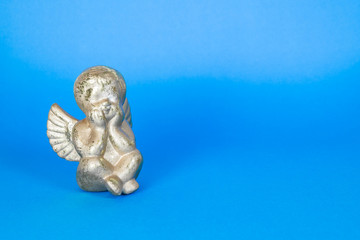 Kleiner sitzender Engel auf blauem Hintergrund