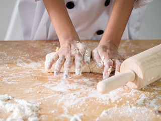 Kid hands in uniform preparing dough for pizza or bread, lifestyle concept.