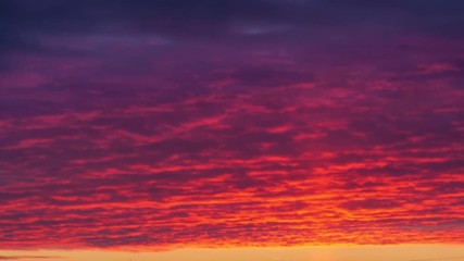 Light pillar atmospheric effect from sunset sun over epic red clouds. Zoom in on dark city skyline. 4K UHD Timelapse.
