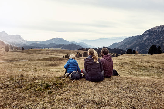 Italy, South Tyrol, Geissler group, family hiking, sitting on meadow