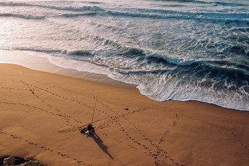 Fisherman on the beach in Portugal, waves and footprints in the sand
