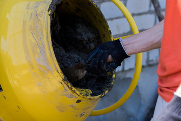 Builder Using Concrete Mixer Works On Building Site. Makes cement mortar. Industrial concept.