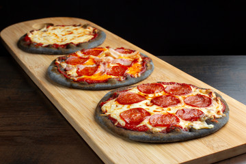 Creative pizza on black dough, three pieces on the board.