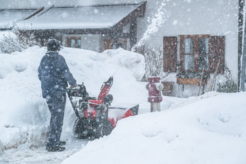 A man cleans snow from sidewalks with snowblower in Bavaria Germany.