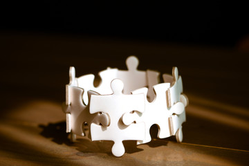 Group of white jigsaw puzzle on wooden table. Business teamwork and collaborate  concept.