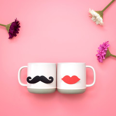 Flower and paper heart shape fake lips and mustaches decoration on pink cup over pink background. Valentine's day and wedding concept. Minimal style.