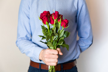 Handsome young man holding red rose bouquet, romantic Valentines day surprise, love,flowers.