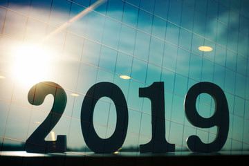 The double exposure image of Happy New Year 2019 overlay with window building image and sun flare. 2019 business concept.