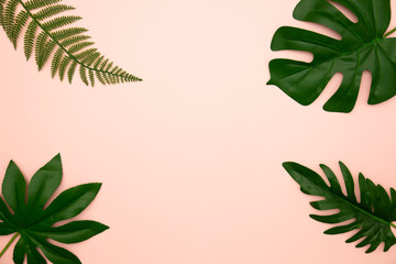 Fototapeta na wymiar Flat lay of green tropical leaves on old rose background with copy space. Vacation holiday travel in summer season concept. Minimal style.
