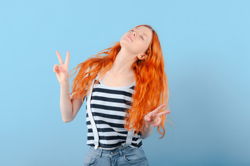 Red-haired girl closed her eyes and shows two fingers