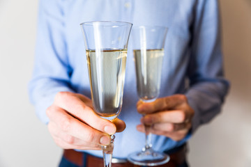 Valentines day romantic date night, handsome man holding two champagne glasses for couple.
