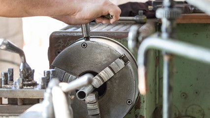 A male worker operating a lathe inside an aluminiun factory.