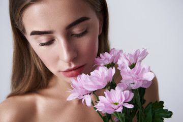 Obraz na płótnie Canvas Charming young woman holding beautiful pink flowers