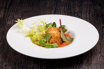 Arancini with marinar sauce and herbs on a wooden background.