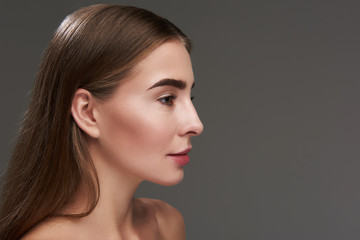 Naklejka premium Beautiful young lady with brown hair posing against gray background