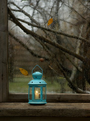 still life with a blue lit lantern on a gloomy window