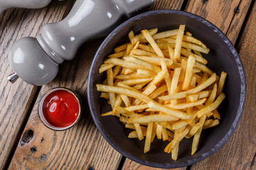 French fries with sauce and pepper on a wooden background.