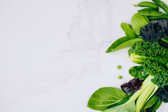 Frame of fresh green vegetables on a marble background, copy space, flay lay, top view