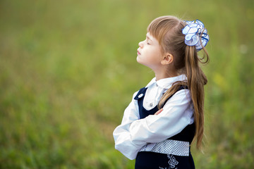 Profile portrait of cute adorable first grader girl in school uniform and white bows in long hair...
