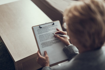 Naklejka premium Top view of woman making notes on clipboard
