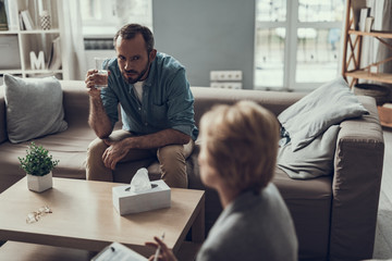 Curious man drinking water and looking at his psychologist