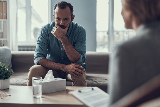 Serious Man Frowning While Sitting In Front Of The Coffee Table