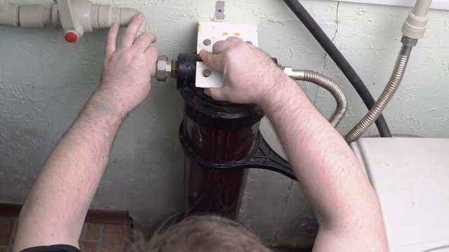 Plumber presses button to drain water before installing new filter.
