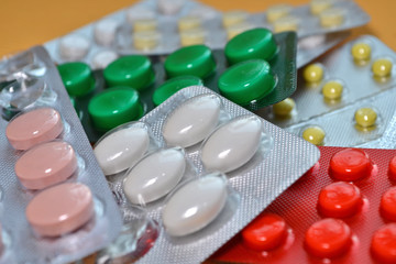 Yellow, white, red, green and pink medical tablets in pack, tablets packed in blisters. Healthcare and medical concept closeup