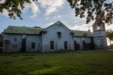 Obraz premium old Spanish Church in Philippines in a sunlight with white clouds and sunbeams on church spire 