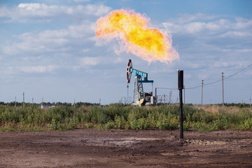 Obraz premium Oil pumpjack and gas torch on oil production