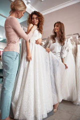Fototapeta na wymiar Beautiful lady fitting dress in wedding salon