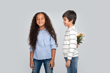 Studio shot of a boy giving flowers to a girl, isolated.