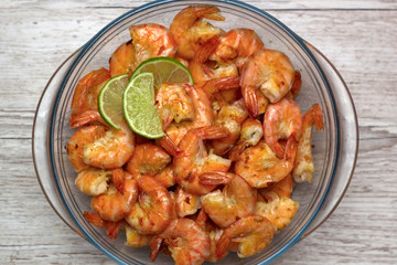 fried roasted shrimps in plate with lime pils in a big glass plate on grey background