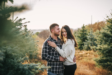 Young couple hugging n the middle of the fir-tree landing