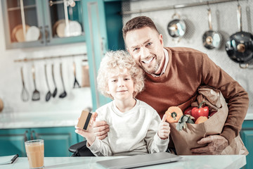 Delighted male person embracing his son with love
