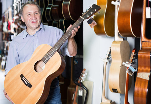 Man choosing new acoustic guitar in music store