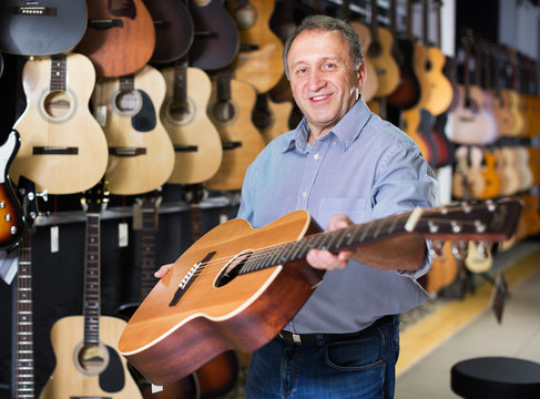 Mature man choosing acoustic guitar