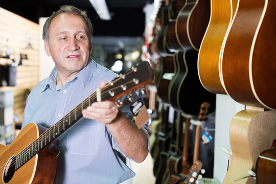 Portrait of man musician looking new acoustic guitar
