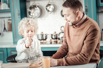 Attentive curly haired boy helping his dad