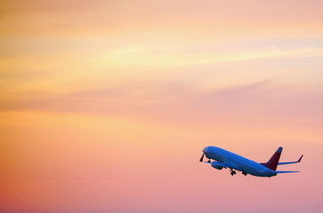 Fototapeta na wymiar Passenger plane taking off over the evening orange sky.