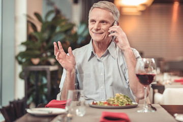 Nice retired man drinking red wine in a restaurant