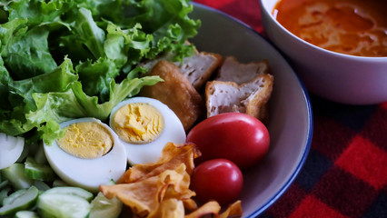 Muslim salad with sauce on wood table and have some space for write wording, delicious appetizer with many kinds of vegetable, green leaf lettuce, onion, boiled egg, tofu, high nutrition