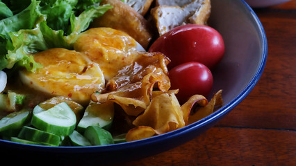 Muslim salad with sauce on wood table and have some space for write wording, delicious appetizer with many kinds of vegetable, green leaf lettuce, onion, boiled egg, tofu, high nutrition