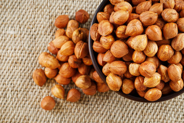 Peeled hazelnuts in a wooden, dark brown cup on a burlap cloth. Super Food, Raw.