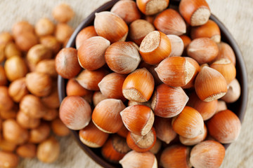 Peeled hazelnuts in a wooden, dark brown cup on a burlap cloth. Super Food, Raw.