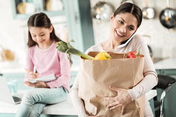 Positive delighted young woman holding package with food